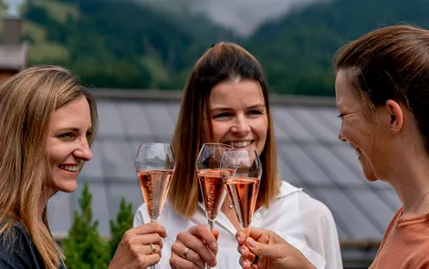 'Good Life' girlfriends' days Women toasting with rosé champagne on a terrace with mountain view